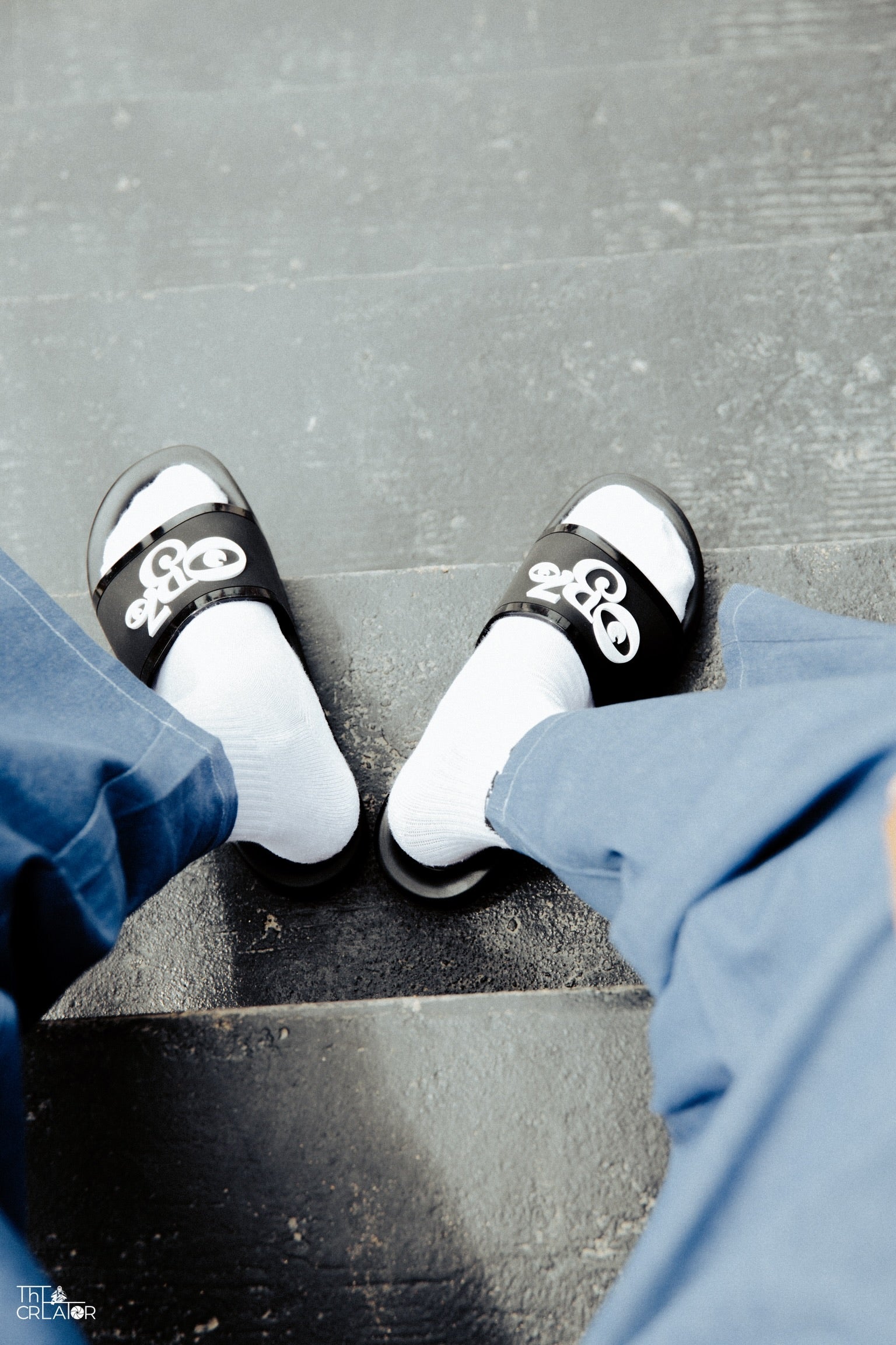 Person wearing black OB70 Classic slide on a gray pavement