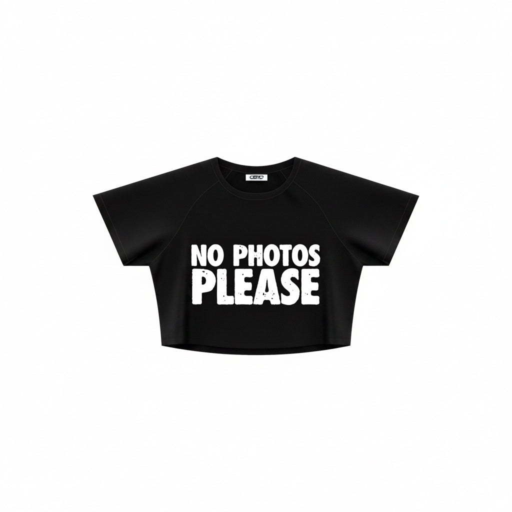 A black short-sleeve crop top t-shirt with 'NO PHOTOS PLEASE' printed in bold white block letters across the chest, shown on a plain white background.