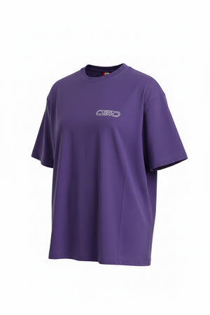 A purple short-sleeve t-shirt with a small white 'OB70' logo on the left chest, laid flat on a dark gray tiled floor.