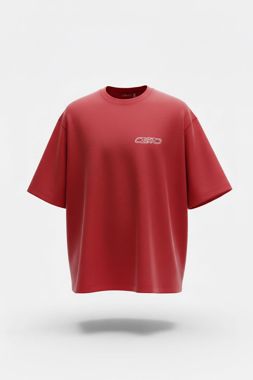 A bright red short-sleeve t-shirt with a small white chest logo, laid flat on a dark gray tiled floor.