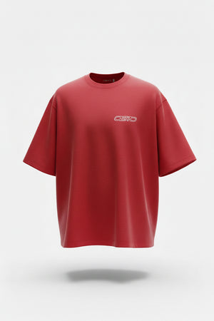 A bright red short-sleeve t-shirt with a small white chest logo, laid flat on a dark gray tiled floor.