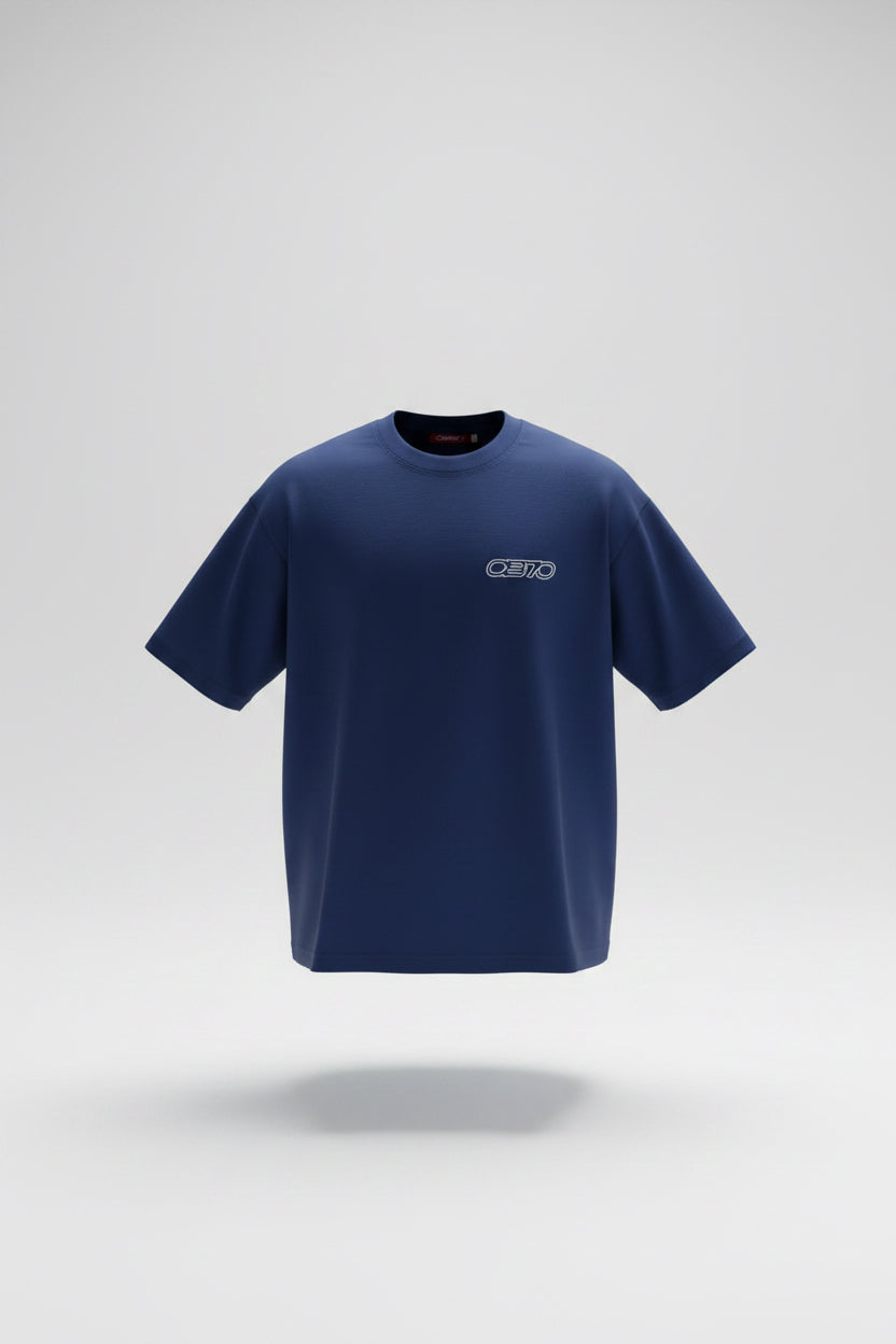 A royal blue short-sleeve athletic t-shirt with a small white 'OB70' logo on the left chest, laid flat on a gray textured tile floor.