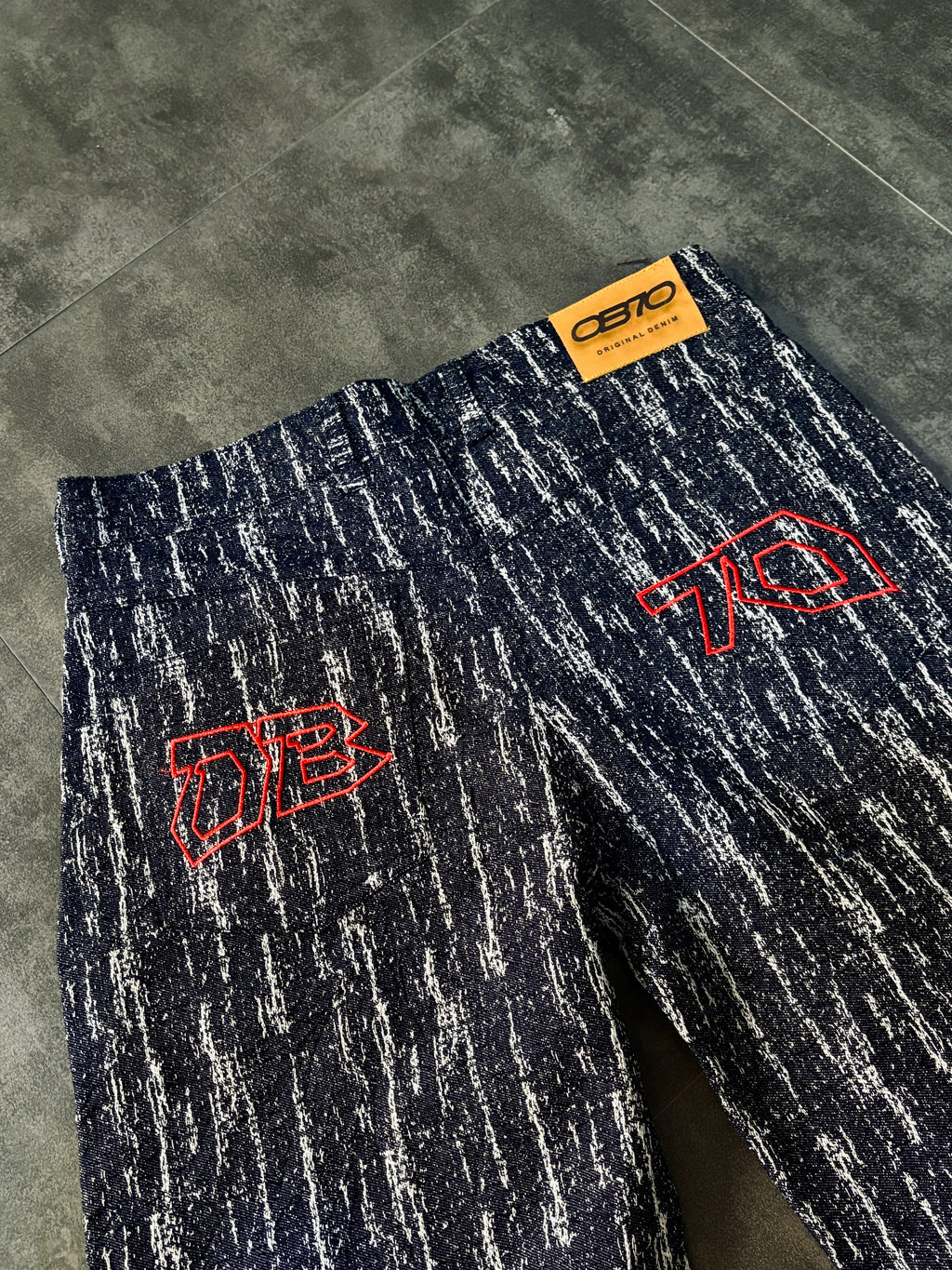Dark blue pants with red logos on a gray floor