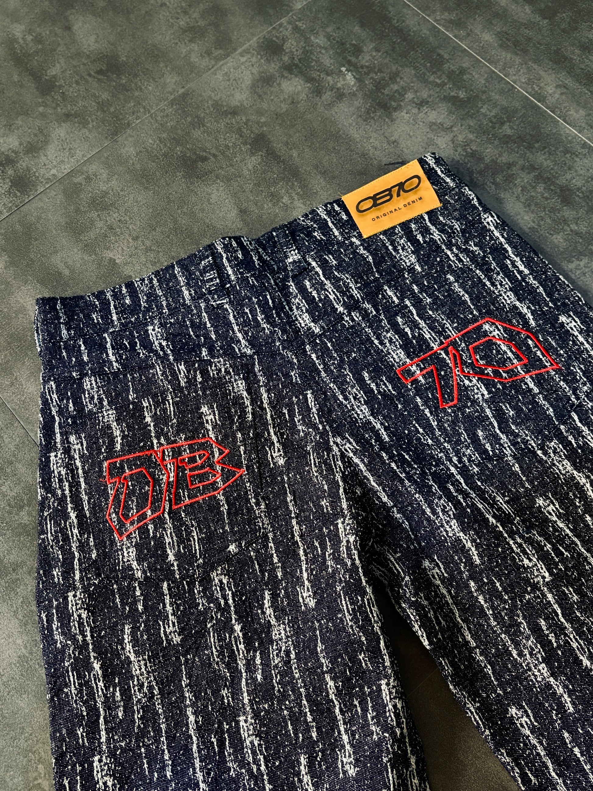 Dark blue pants with red logos on a gray floor