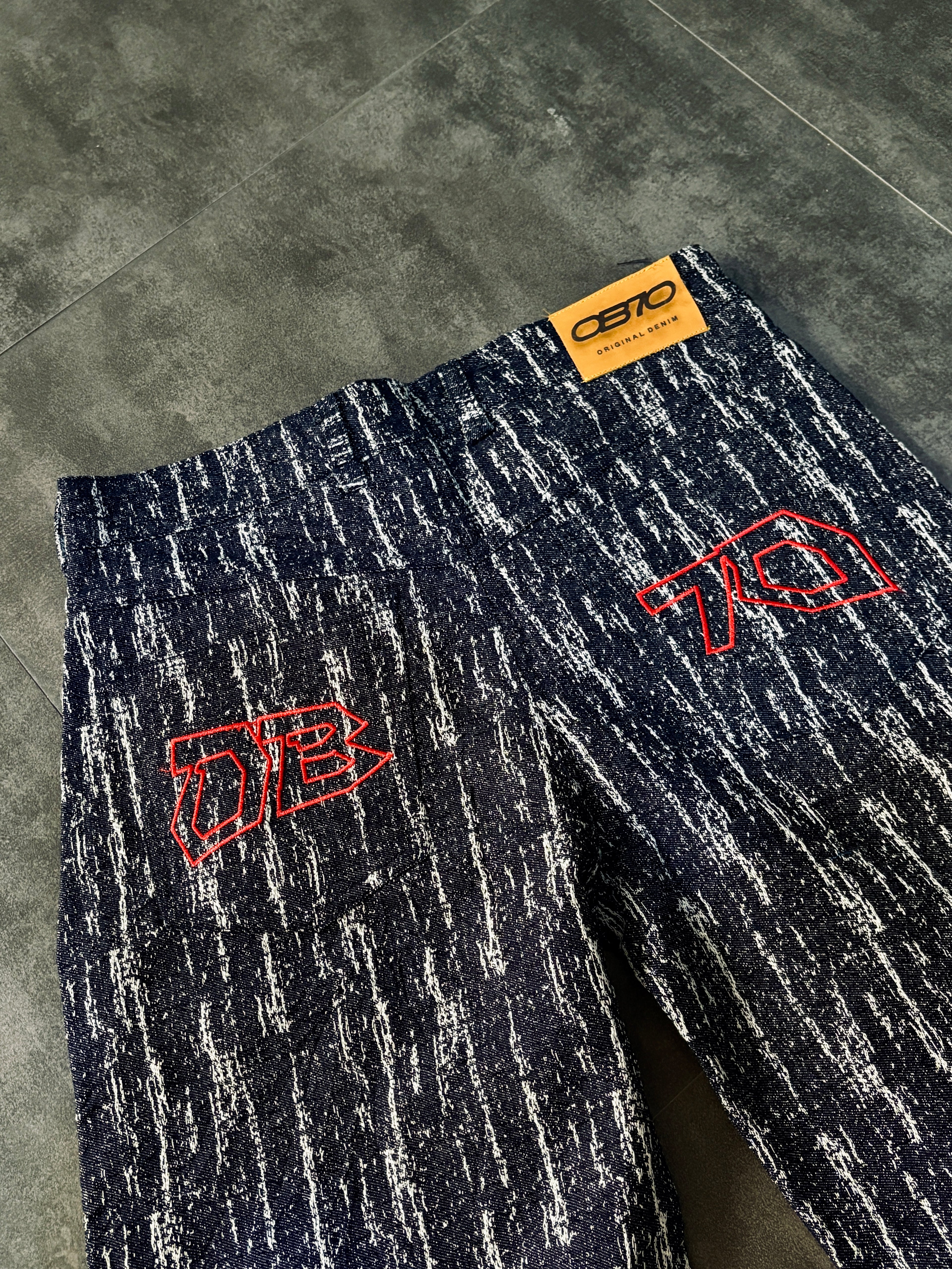 Dark blue pants with red logos on a gray floor