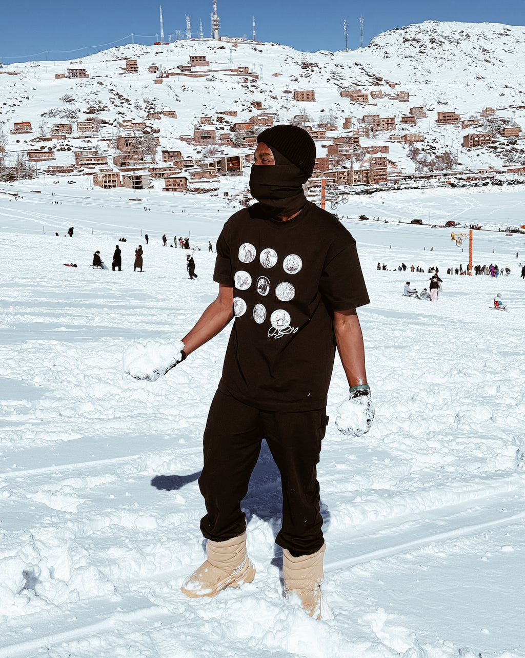 Person in black outfit with white polka dots on a snowy landscape with buildings in the background