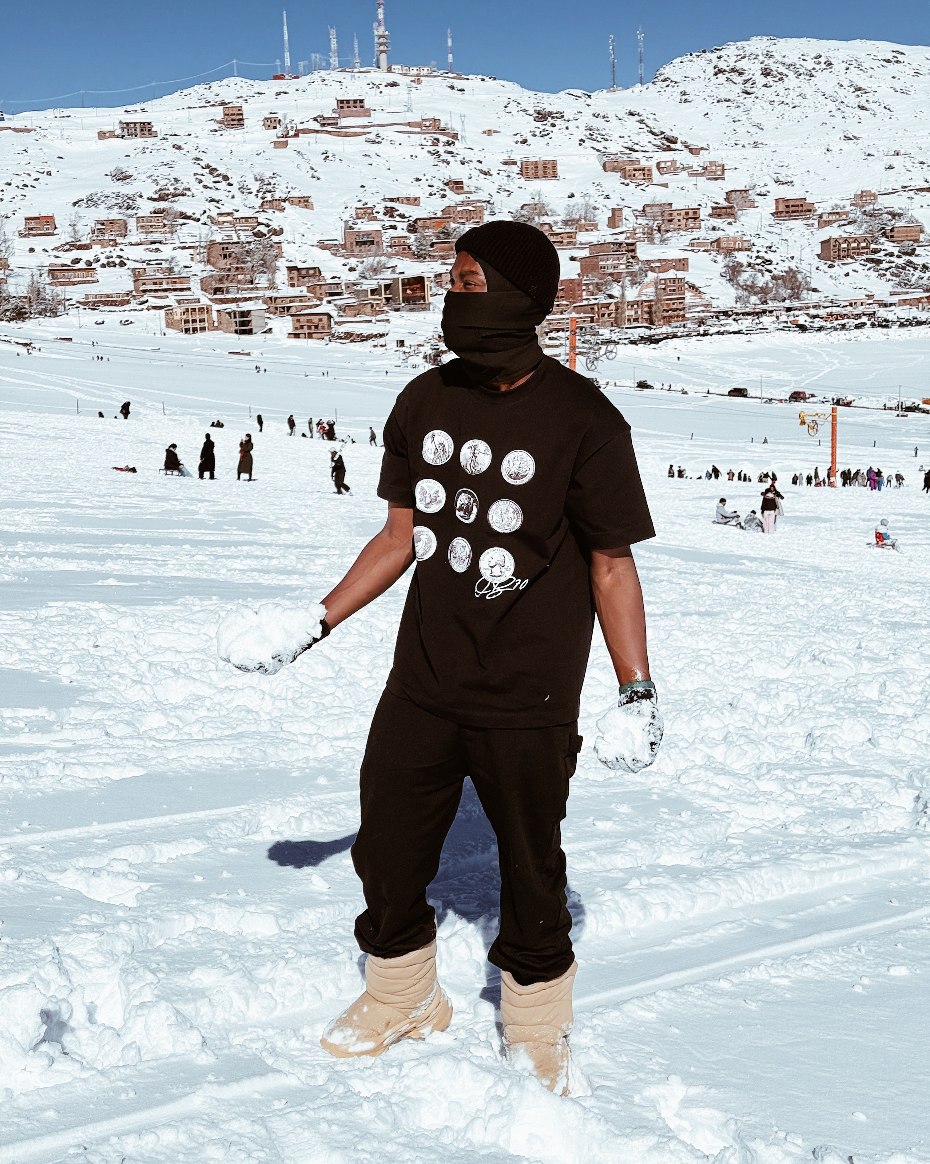 Person in black outfit with white polka dots on a snowy landscape with buildings in the background